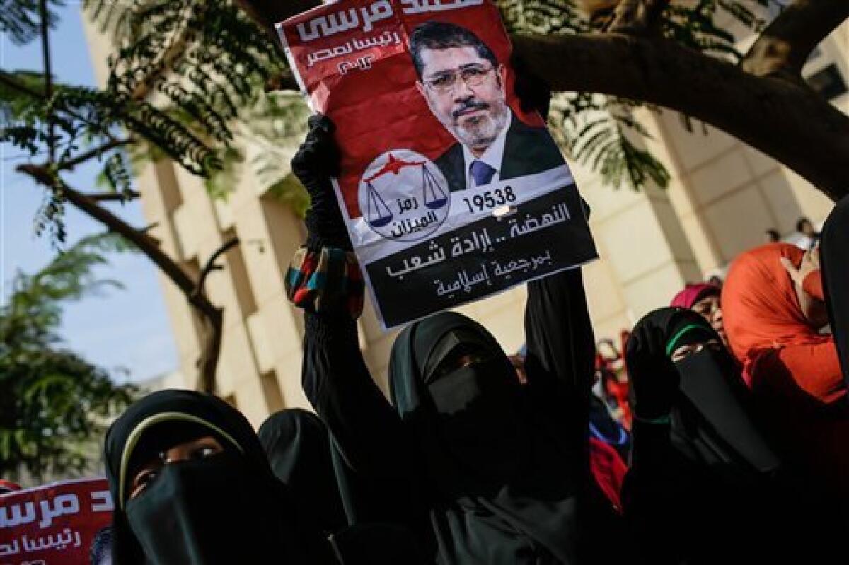 In Cairo, a supporter of ousted Egyptian president Mohamed Morsi holds an old campaign poster that reads, "Mohamed Morsi, president for Egypt, 2012, resurrection is the will of the people," during a protest on the eve of the former leader's trial.