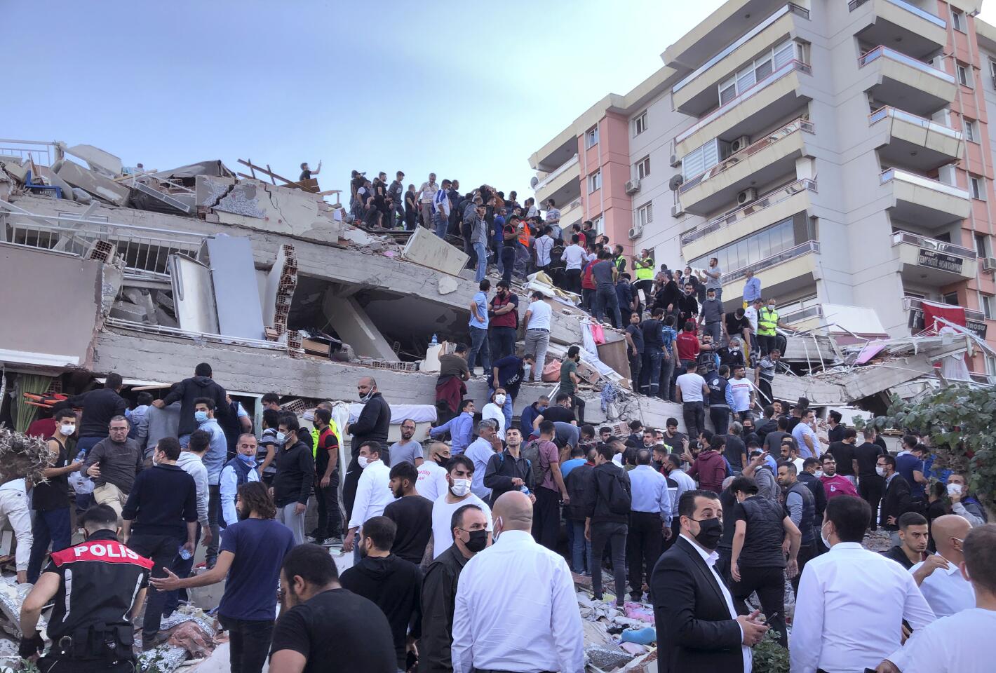 Rescue workers try to reach residents trapped in the debris of a collapsed building, in Izmir, Turkey