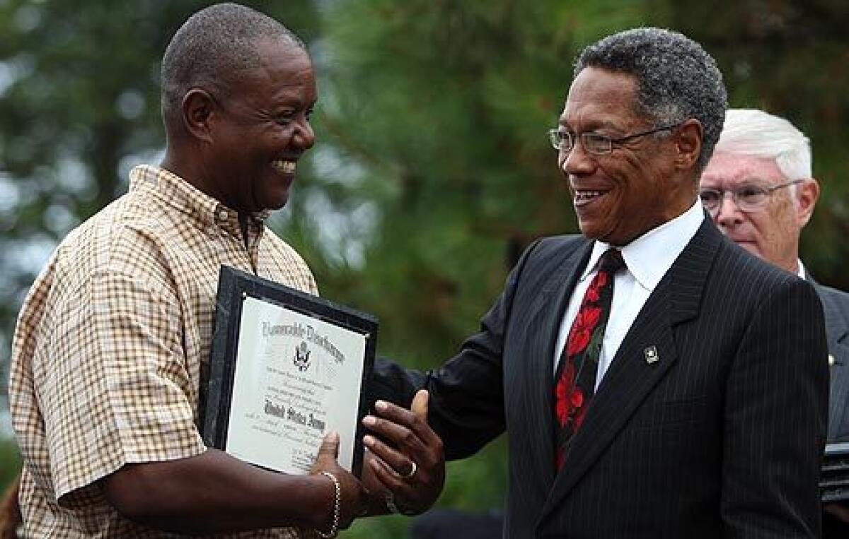 HONORABLE DISCHARGE: Ray Snow, left, accepts the official honorable discharge for his father, Samuel, from Ronald J. James, an assistant Army secretary presiding over the ceremony at Seattle's Ft. Lawton. Samuel Snow was among 28 black World War II soldiers wrongly convicted in the 1944 lynching of an Italian prisoner. Now 83 and one of only two of the 28 still alive, he fell ill earlier in the day and was unable to attend. More photos >>>