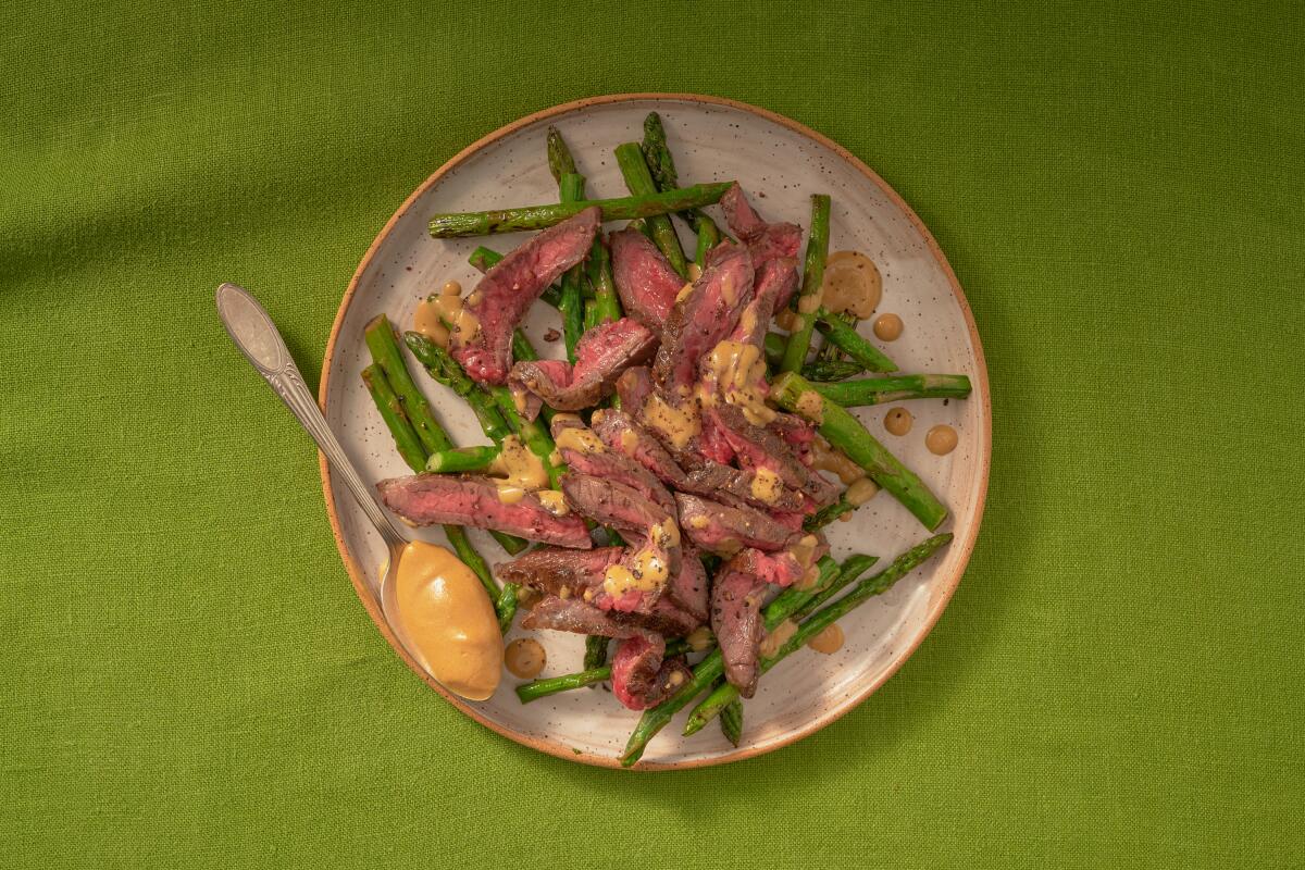 An overhead shot of steak with mustard sauce and asparagus
