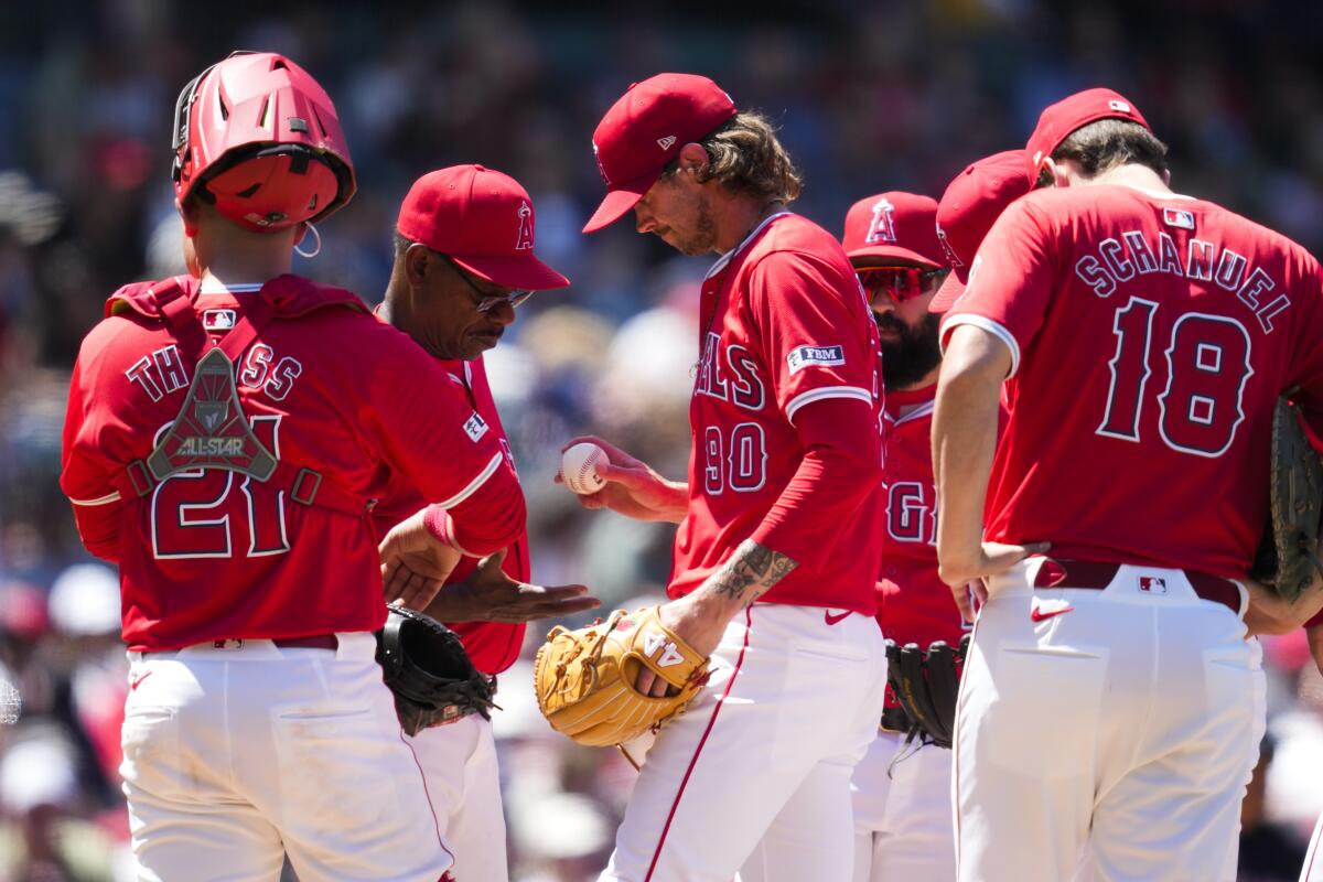 Pitcher Adam Cimber hands the ball to manager Ron Washington as teammates look disconsolate