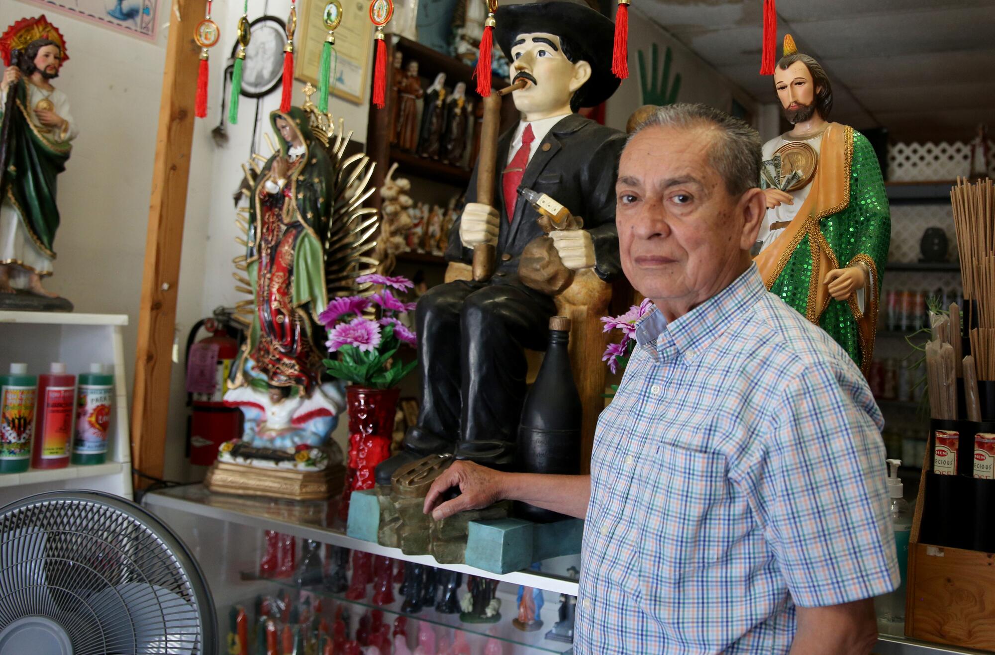 A man stands next to a large statue of Jesus Malverde, the "angel of the poor." 