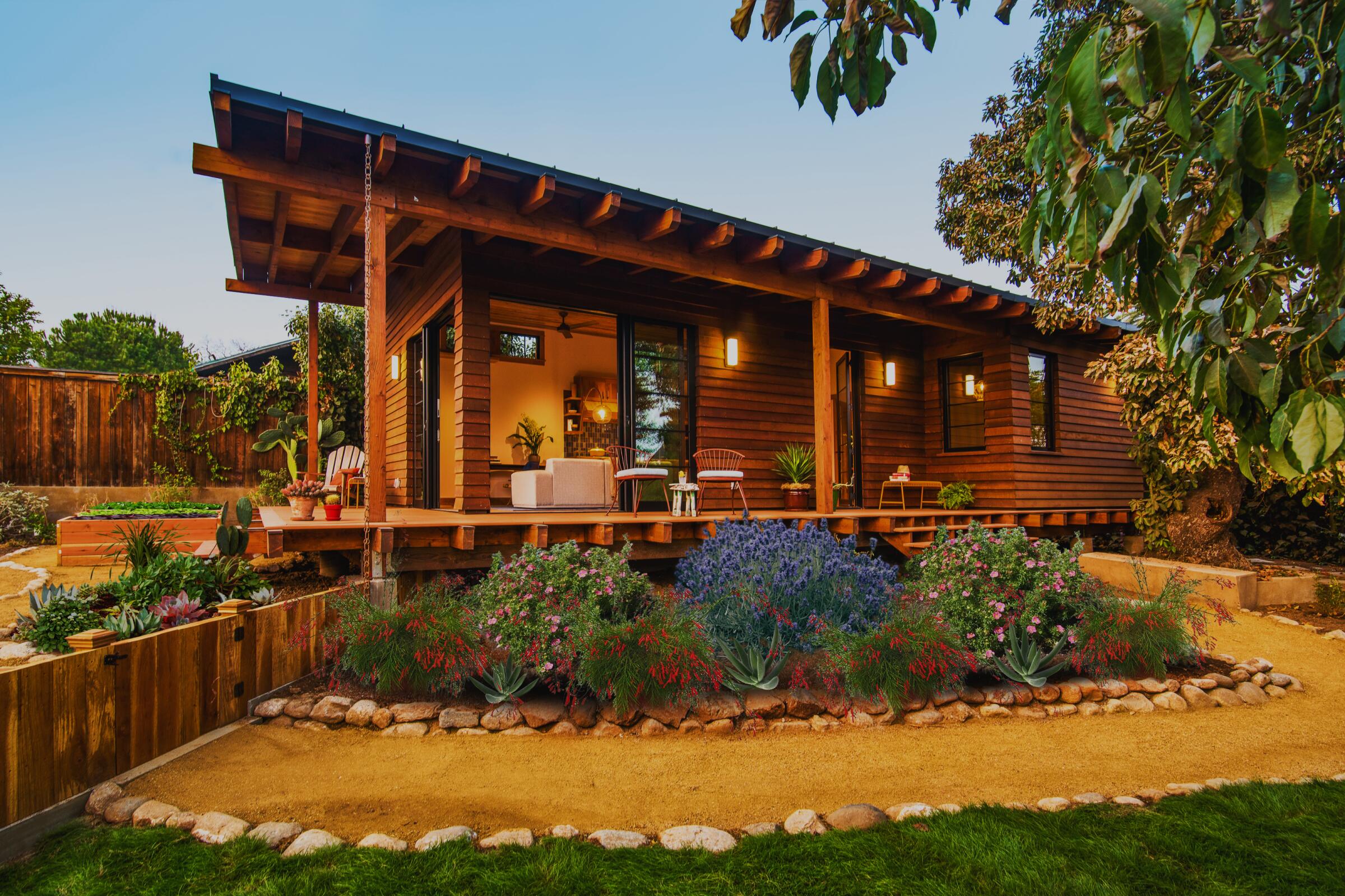 An exterior shot of a quaint 'granny flat' with redwood siding and a wraparound deck