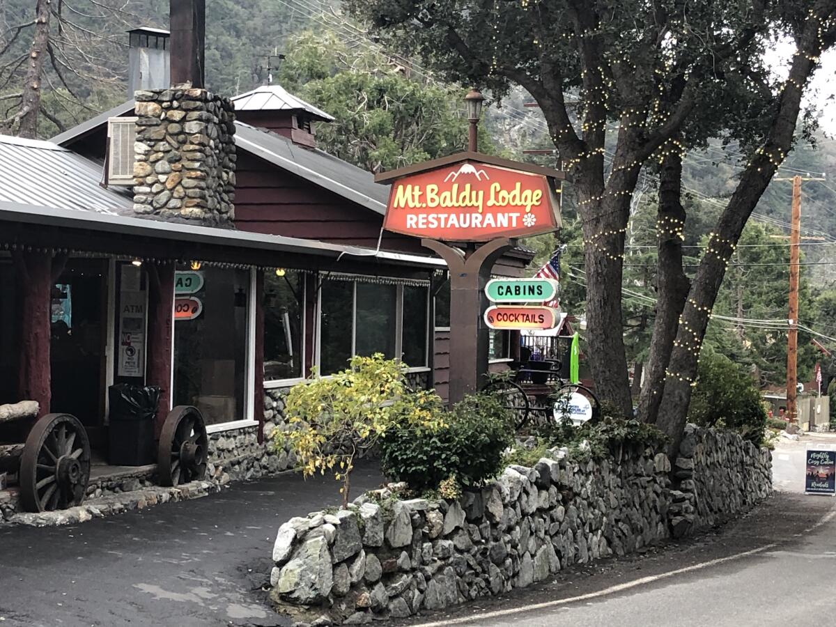 A small brown building with a fieldstone chimney has a sign that says "Mt. Baldy Lodge Retaurant."