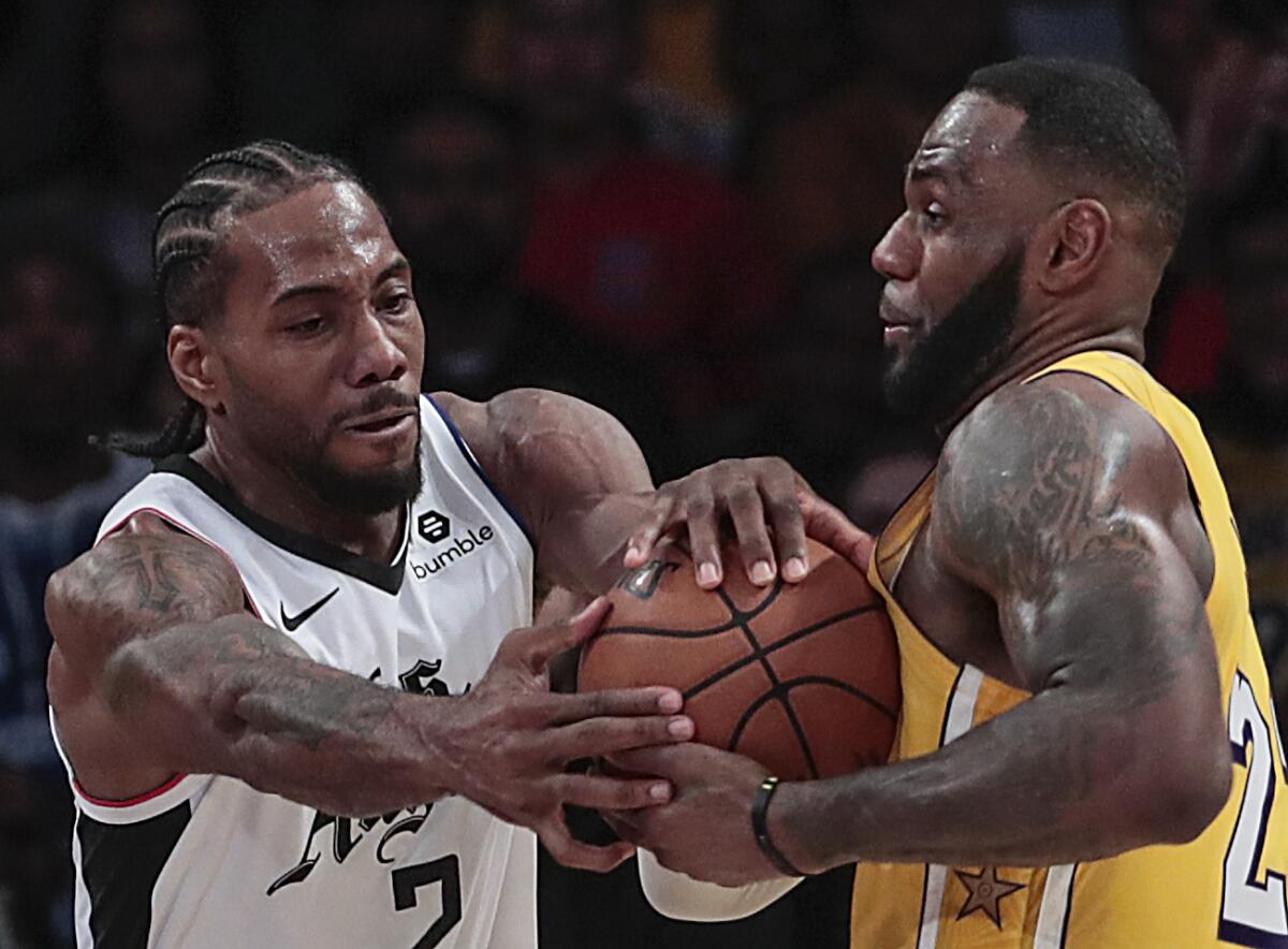 Clippers forward Kawhi Leonard and Lakers forward LeBron James battle for a loose ball during a game Dec. 25, 2019.