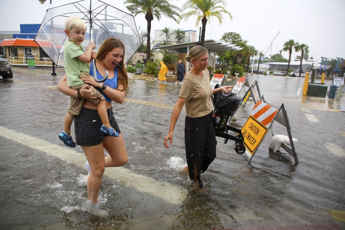 A family walks through a flooded street during Tropical Storm Debby.