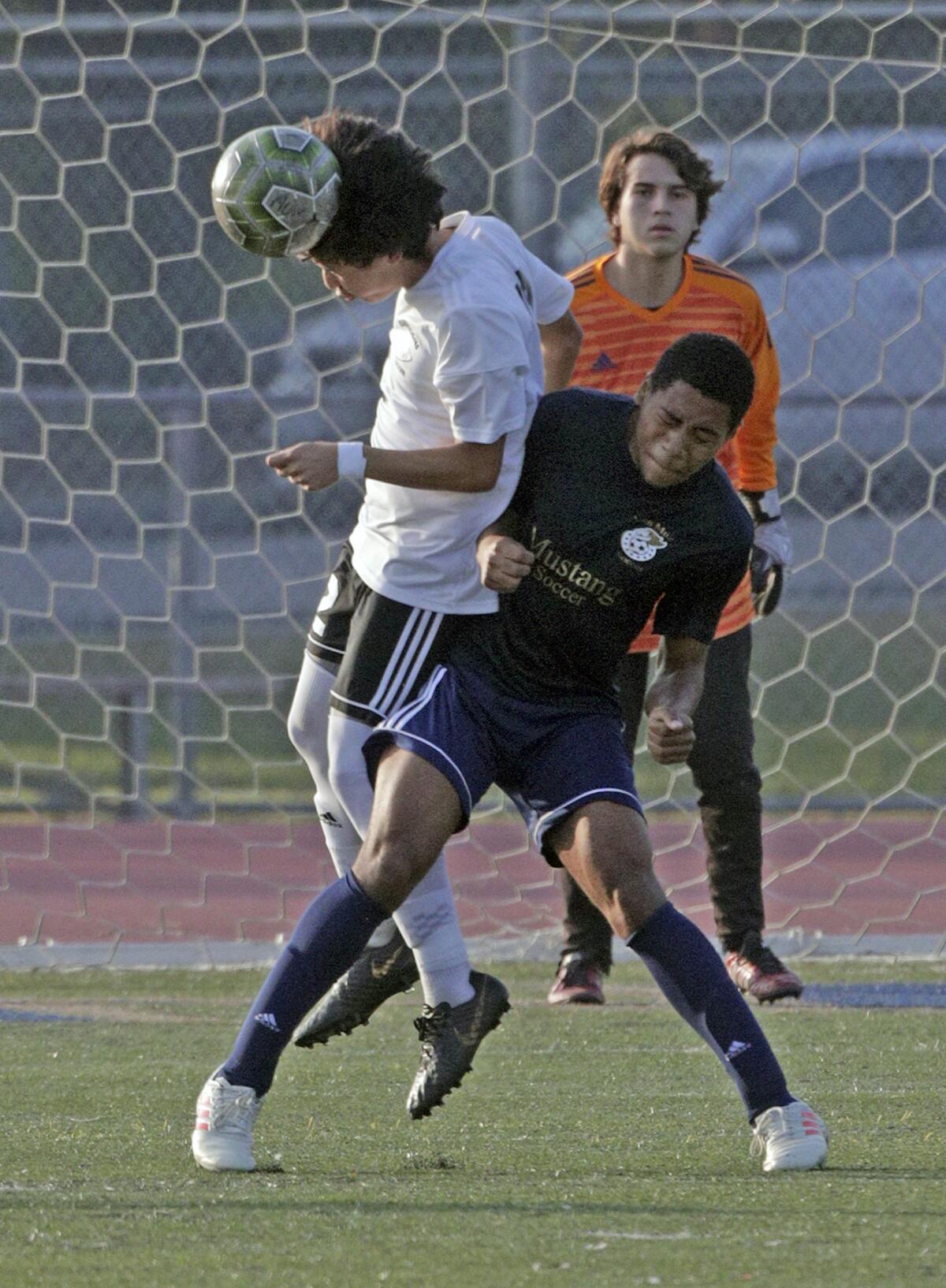 Burroughs' Jaden Vasquez heads the ball just as Muir throws a hip out to throw Vasquez off balance in a Pacific League boys' soccer game at Muir High School in Pasadena on Tuesday, January 14, 2020.