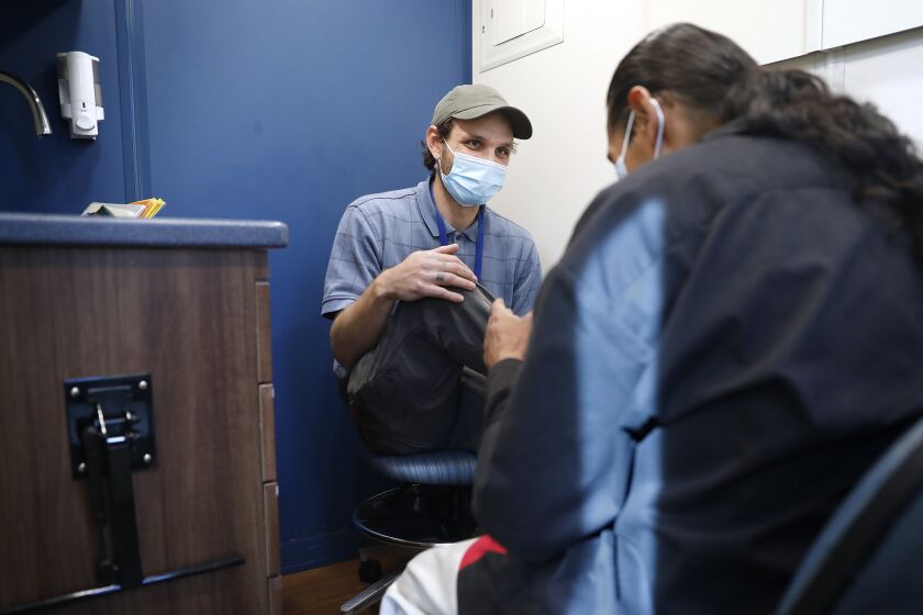 LOS ANGELES-CA-DECEMBER 16, 2022: Field supervisor Jordan Spoliansky, left, chats with Michael Mendez, 47, a program participant, inside a UCLA Health mobile clinic that is part of a study that is assessing the effectiveness of a "one stop" mobile unit to link people who inject drugs to health services, including treatment for hepatitis C., on Friday, December 16, 2022. (Christina House / Los Angeles Times)