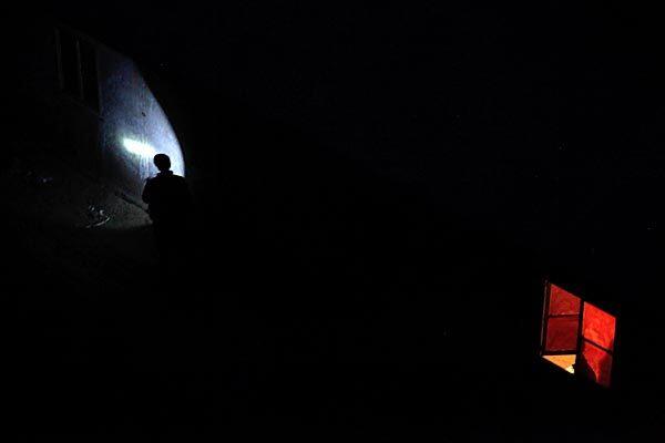 A man finds his way in the dark with a light near the living quarters of the Wangjialing Coal Mine in Xiangning county in north China's Shanxi province Tuesday. Floodwaters kept rescuers from reaching 33 miners still trapped in a Chinese coal pit, and the recovery of five bodies dimmed hopes of another miracle a day after 115 survivors were pulled out after more than a week underground.