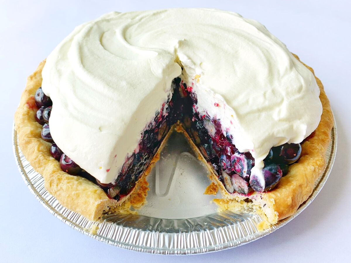 Fresh Blueberry Pie in a tin with one slice missing.