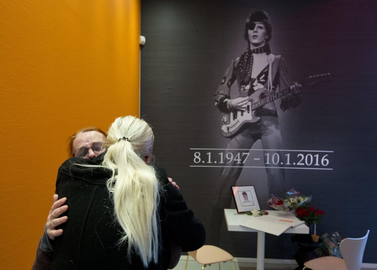 A crying woman, left, is comforted after signing a book of condolences for pop star David Bowie at the Groninger Museum, which is hosting the "David Bowie Is..." exhibition.