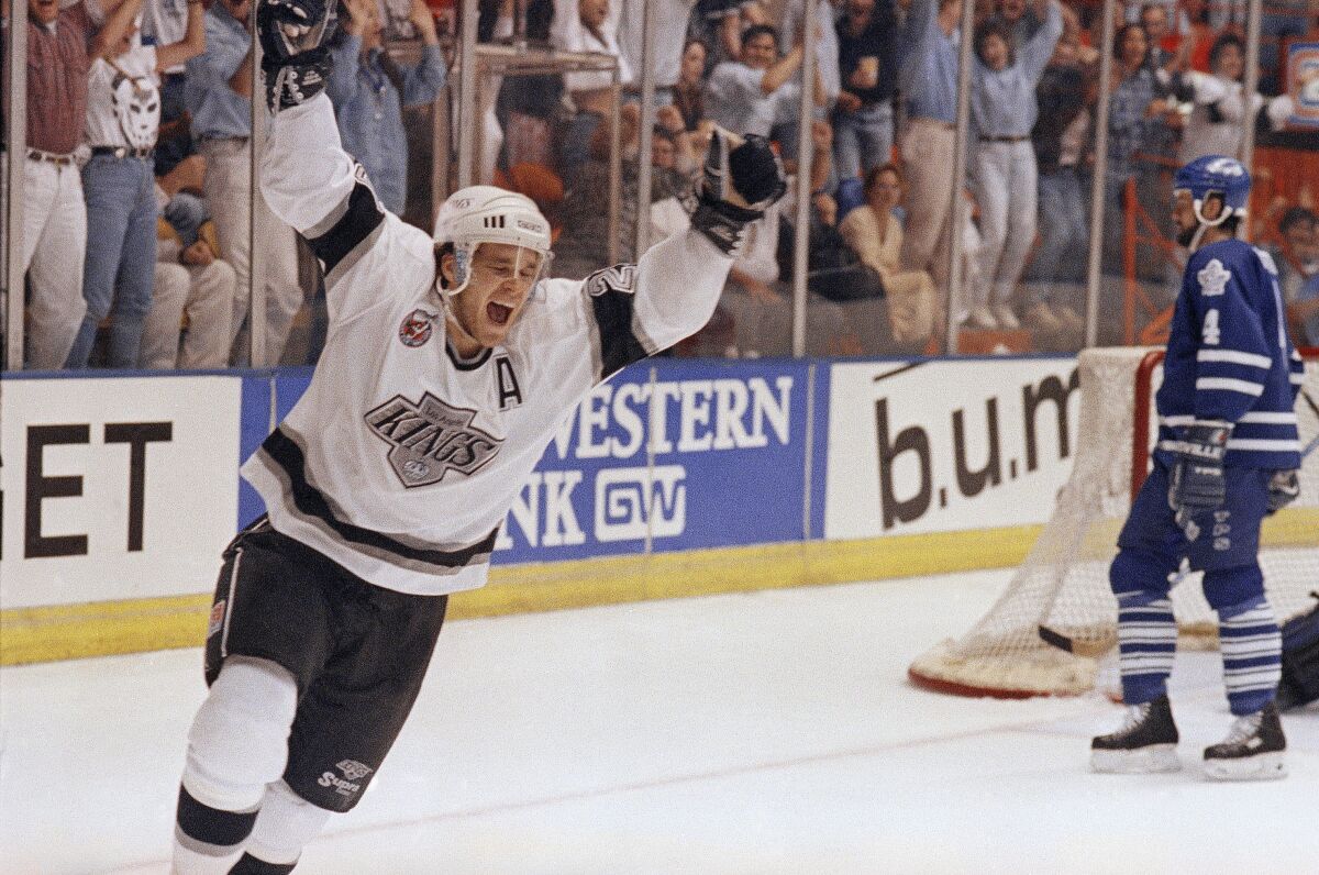 Luc Robitaille raises his arms after scoring a goal and the audience behind him does the same