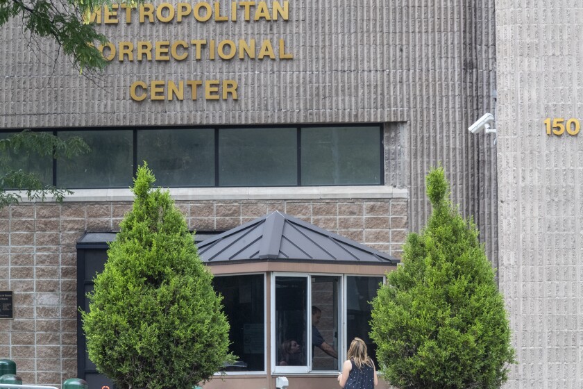 FILE - In this Aug. 13, 2019 file photo, an employee checks a visitor outside the Metropolitan Correctional Center in New York. The warden brought in to clean up the embattled federal jail where Jeffrey Epstein killed himself has abruptly stepped down after a year-long tenure marred by the rampant spread of coronavirus, inmates complaints about poor conditions, a gun smuggled into the facility, and an inmate's death. (AP Photo/Mary Altaffer, File)