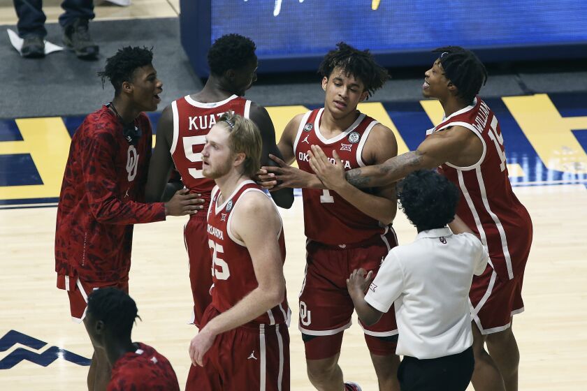 Oklahoma players celebrate after defeating West Virginia in double-overtime Feb. 13, 2021, in Morgantown, W.Va.