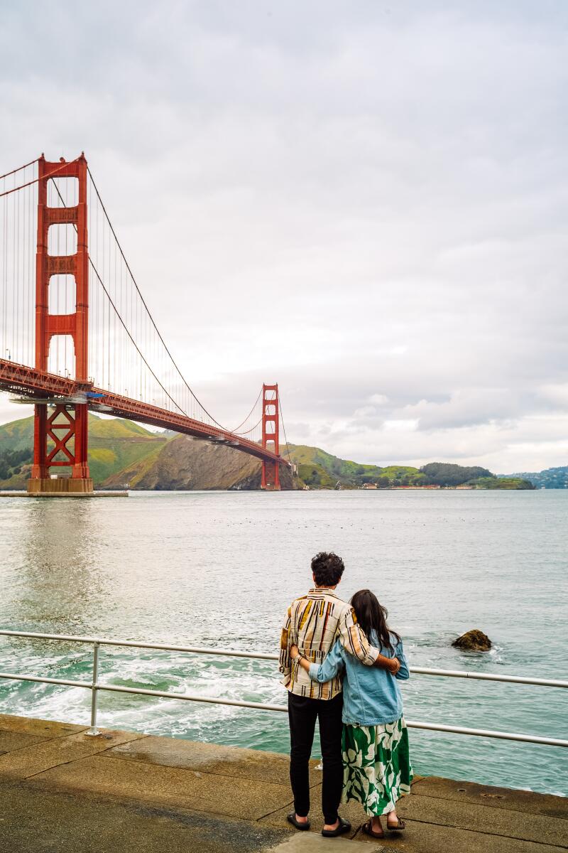 A couple hunts while looking at the Golden Gate Bridge from Fort Point in San Francisco.