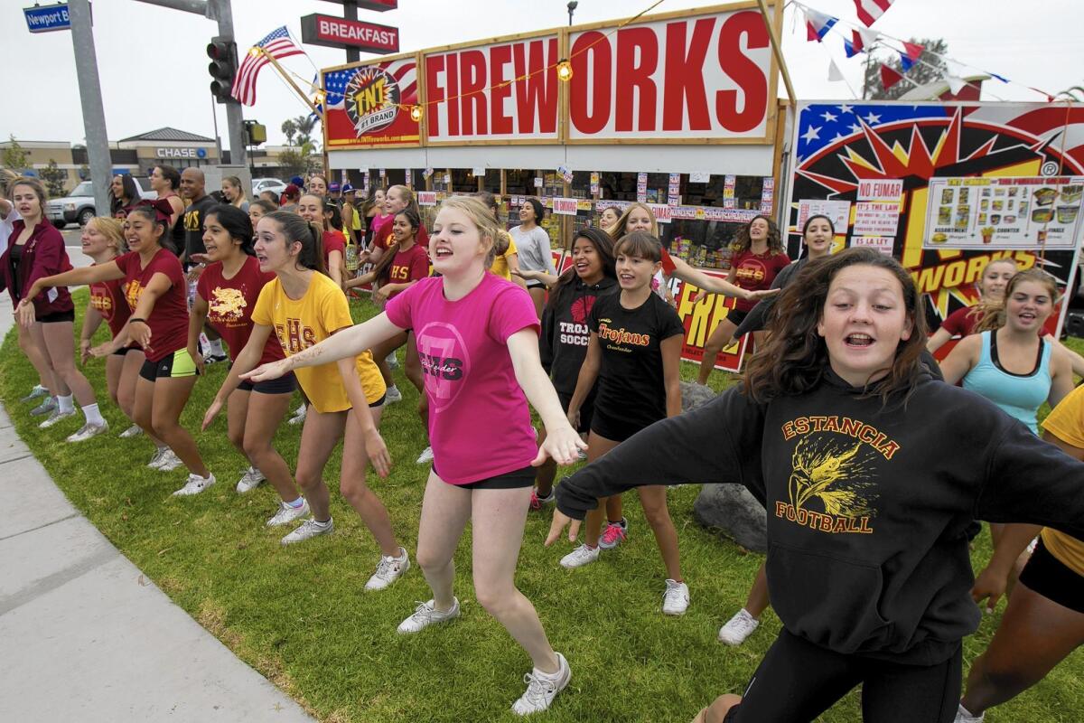 Members of the Estancia High School cheer squad practice in front of the group's fireworks stand in Costa Mesa in 2014. Local groups say the proceeds from such stands are important fundraising sources.