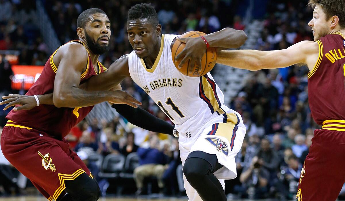 Pelicans point guard Jrue Holiday tries to drive between Cavaliers point guard Kyrie Irving, left, and guard Matthew Dellavedova in the second half Friday night in New Orleans.