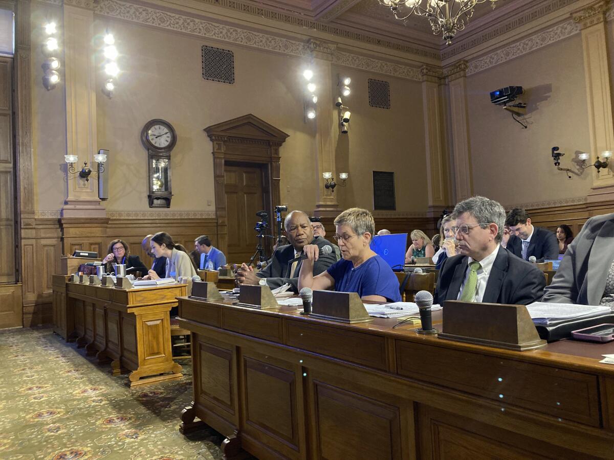 People sit at desks in a hearing room
