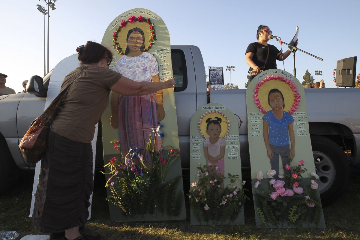 San Diego artist Antonia Davis moves a piece of her artwork that she said represented migrant children killed by U.S. policy as another woman speaks to the crowd during a protest rally demanding the closure of migrant detention camps Friday in San Ysidro.
