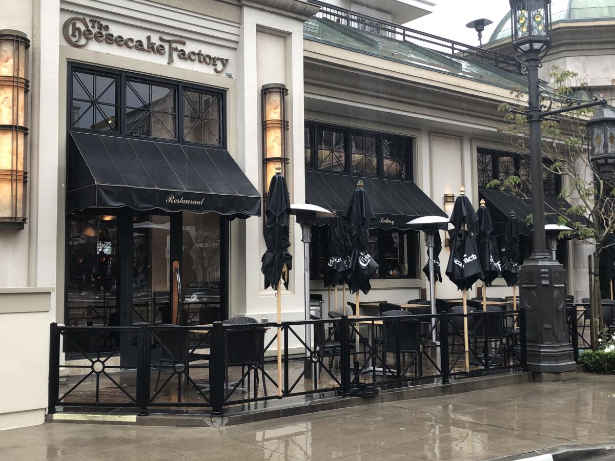 Umbrellas were shut at the Americana's Cheesecake Factory in a closed outdoor dining area.