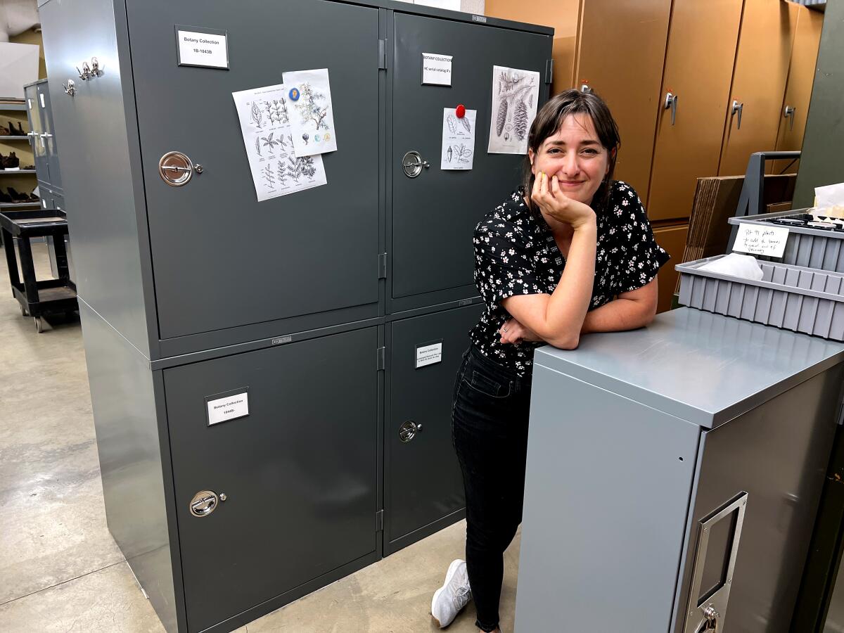 Jessie George in front of a cabinet holding flora found at La Brea Tar Pits.