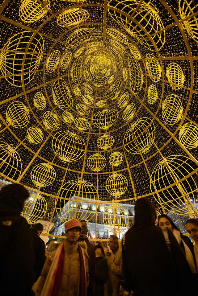 People pass under a giant Christmas tree -- it seems to go on forever -- illuminating the Puerta del Sol, a spot popular with tourists and locals.