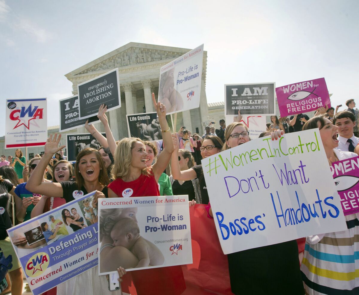 Protesters stand before the U.S. Supreme Court in Washington on June 30 after the court sided with businesses seeking to refuse coverage of contraceptives under the Affordable Care Act.