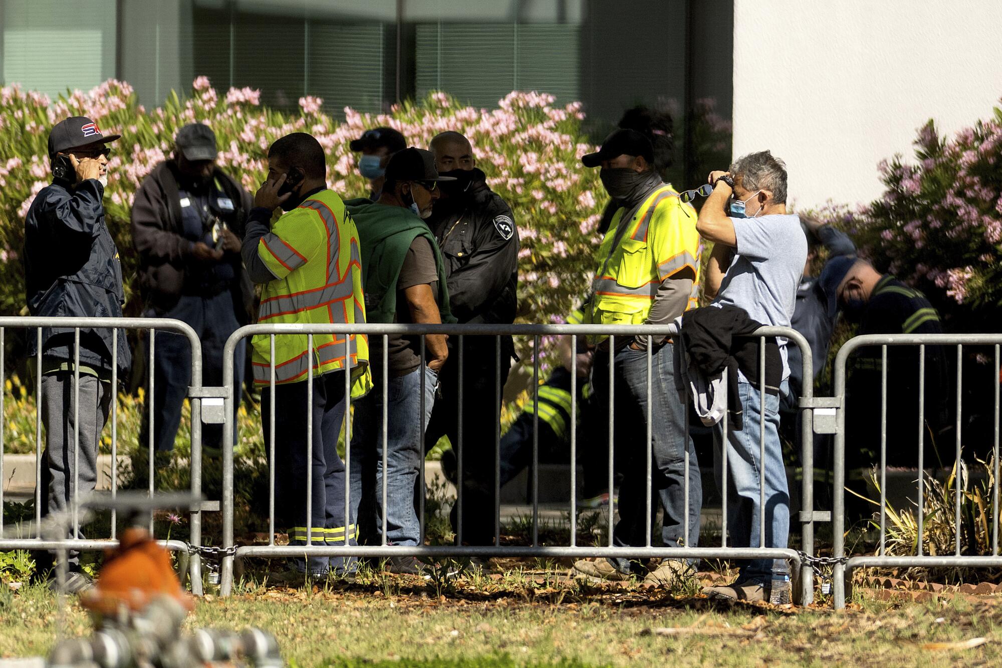 People stand behind a low metal barrier.