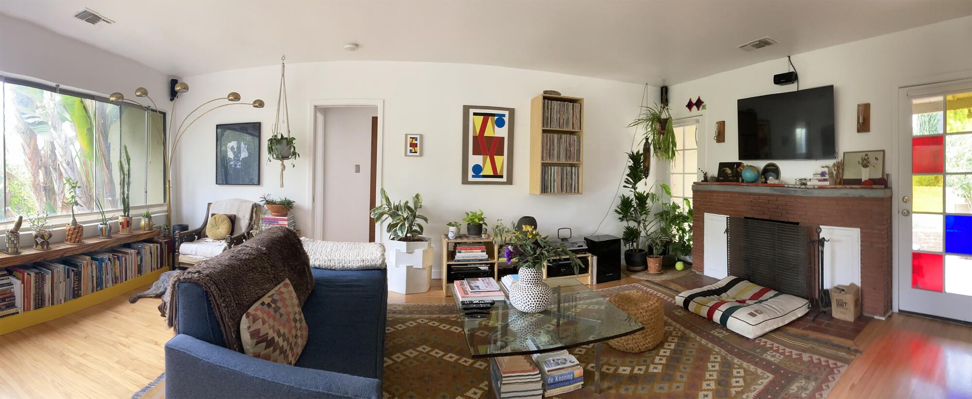 A living room with a red brick fireplace and colorful artworks.