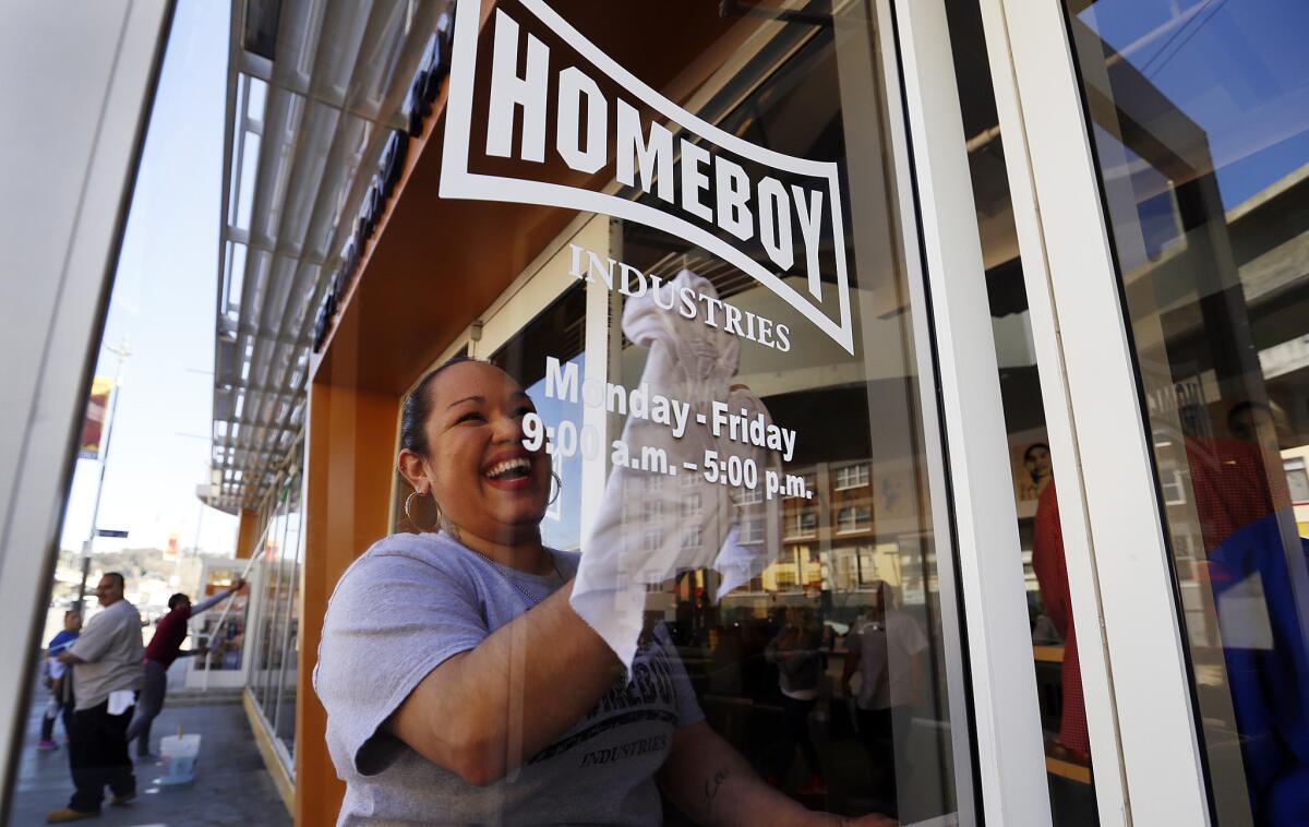 Ilenee Velasco cleans the front door of the headquarters of Homeboy Industries in March. Nonprofits that hire and train disadvantaged and out-of-work clients, such as Homeboy, won't have to pay them Los Angeles' new minimum wage for the first year and a half of their employment.