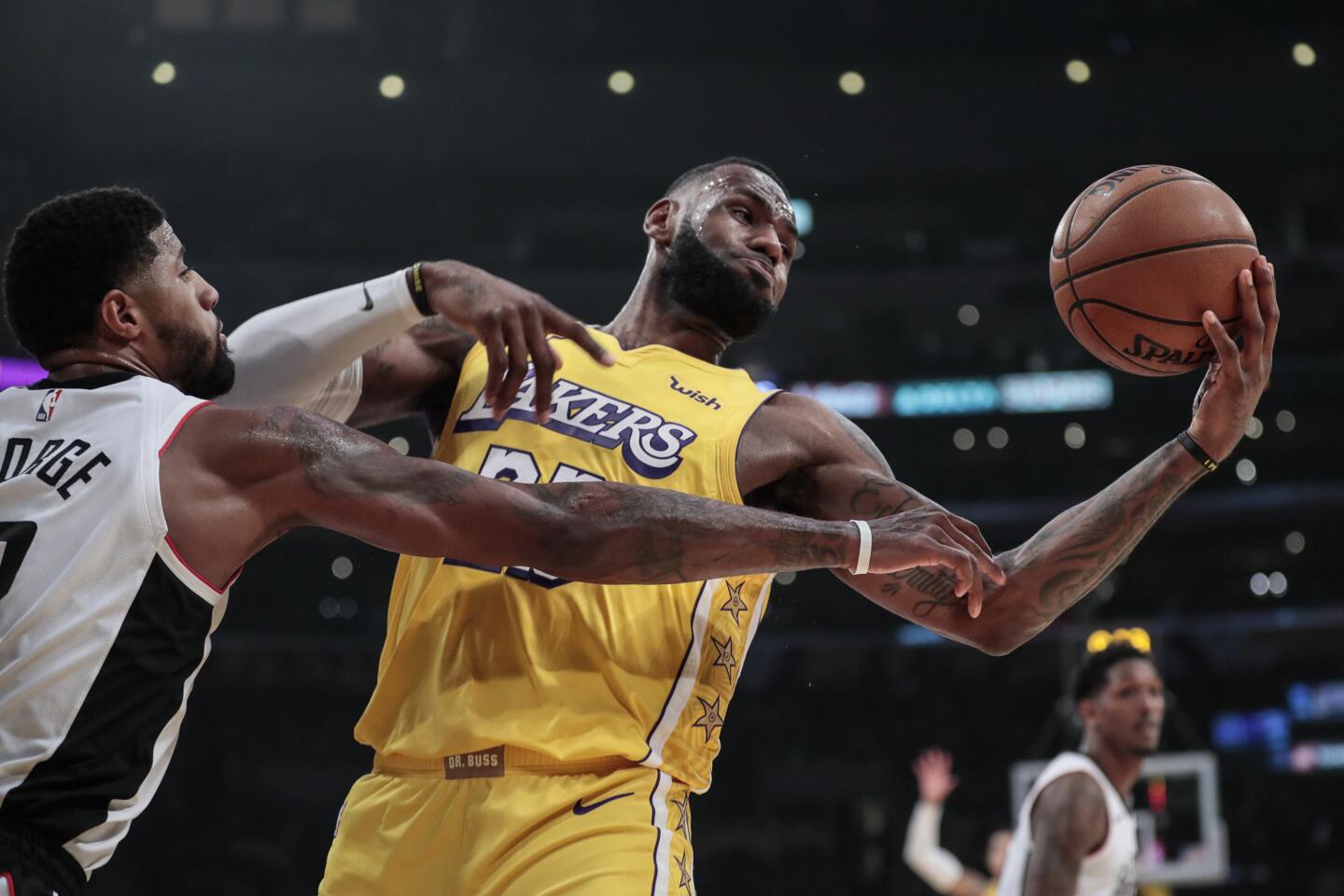 Lakers forward LeBron James tries to control a rebound against Clippers forward Paul George.