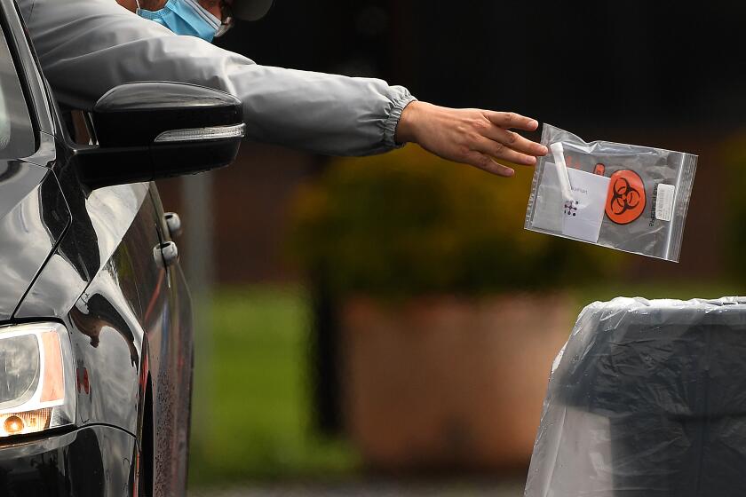 LOS ANGELES-CA-APRIL 8, 2020: A specimen is turned in at the new mobile testing site for people with symptoms of the coronavirus at Charles R. Drew University of Medicine and Science in South Los Angeles on Wednesday, April 8, 2020. (Christina House / Los Angeles Times)