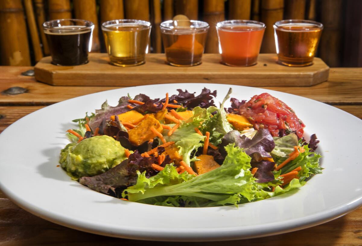 Keep it healthful with  Kekela greens at Big Island Brewhaus in Kamuela, Hawaii.  In the background are Brewhaus draft beer samplers, your pick of five 3.5-ounce glasses, $7.50.