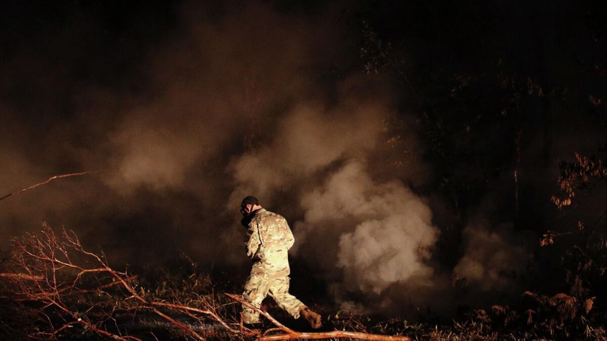 On Thursday, Sgt. Carl Satterwaite of the National Guard tests air quality near cracks emitting volcanic gases from a lava flow on Hawaii Island. Kilauea has destroyed more than 24 homes since it began releasing lava from vents about 25 miles east of the summit crater.