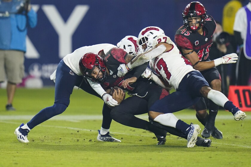 San Diego State quarterback Lucas Johnson gets tackled by two Fresno State players during Saturday night's game.