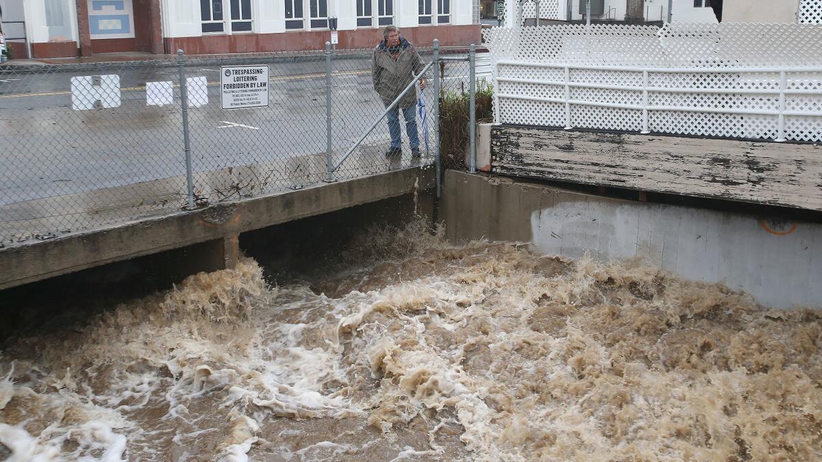 Rushing storm water from Laguna Canyon pours down a drain on Beach Street in downtown Laguna Beach during Thursday’s rain.