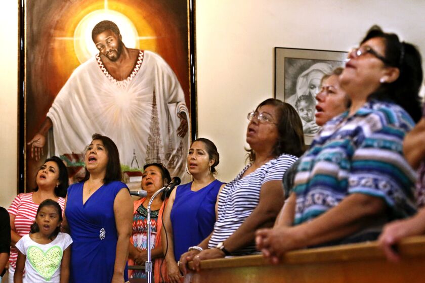 Members of St. Lawrence Brindisi Church on Compton Avenue in Watts sing during Sunday morning Mass on July 26, 2015. In the background is a painting known as "Jesus of Watts" that was donated to the church some 20 years ago.