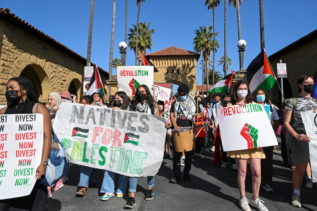 Protesters hold signs reading "Natives for Palestine" and "Divest Now."