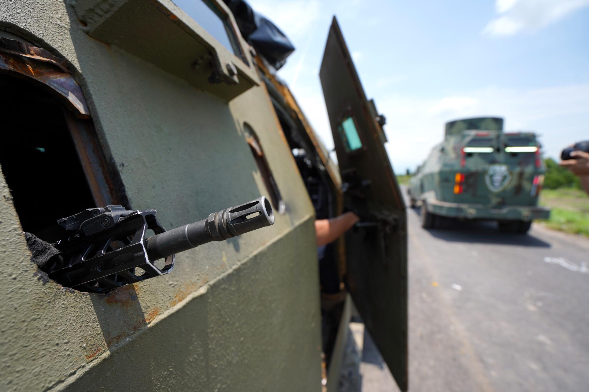 Close up of a vehicle with a rifle muzzle outside a window.