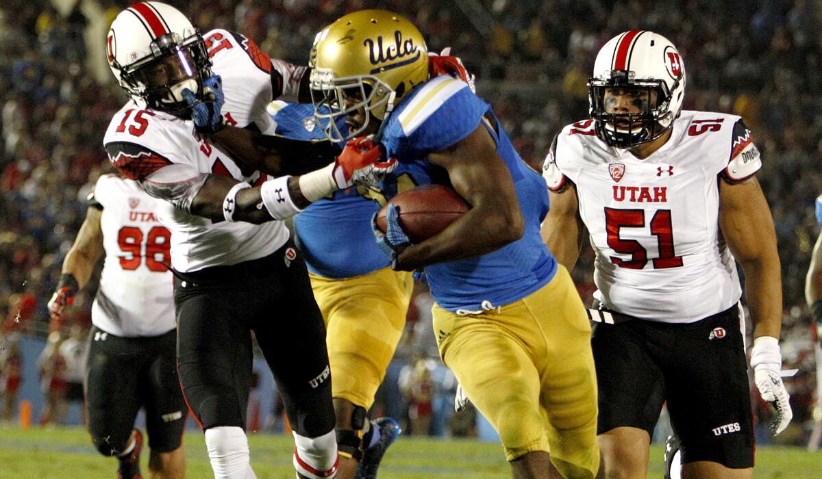 UCLA running back Paul Perkins gains 22 yards before being pulled down by Utah cornerback Dominique Hatfield (15) near the goal line in the second quarter Saturday night at the Rose Bowl.