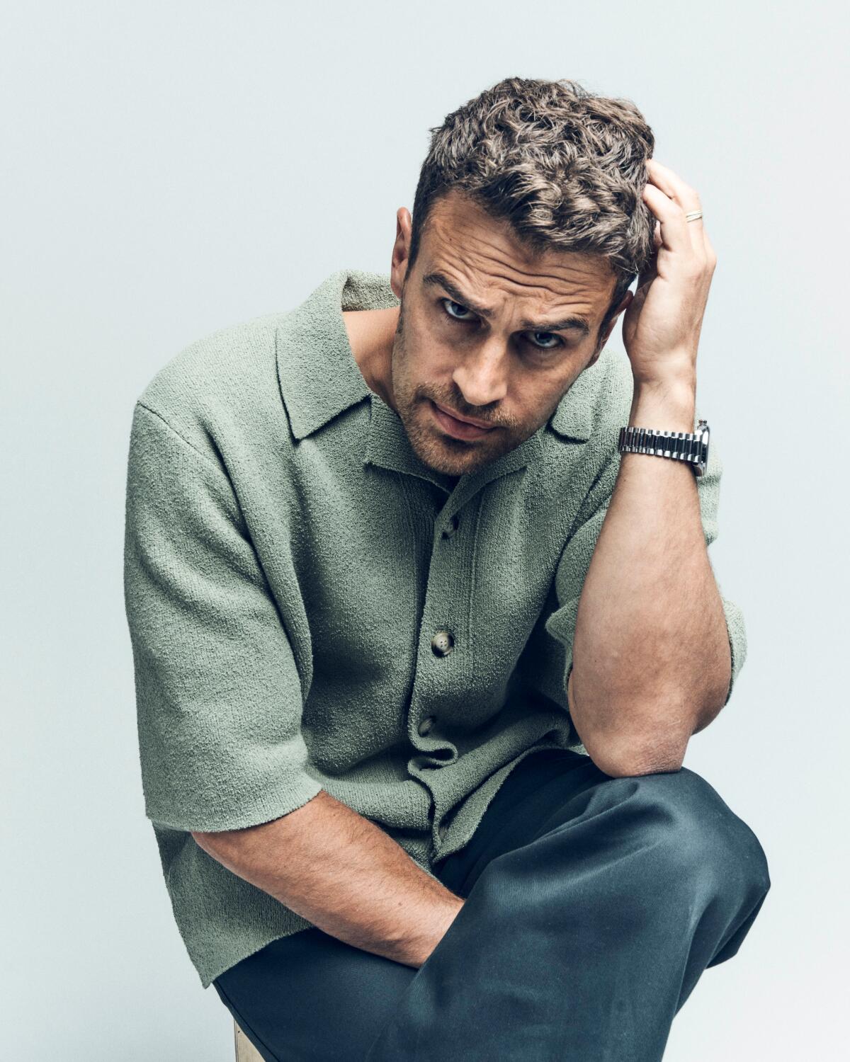 Theo James puts a hand to his head as he sits for a portrait.