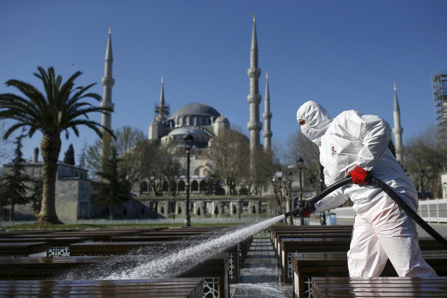 Turkey: A municipality worker wearing a face mask and protective suit disinfects chairs outside the historical Sultan Ahmed Mosque, also known as Blue Mosque in Istanbul, Turkey.