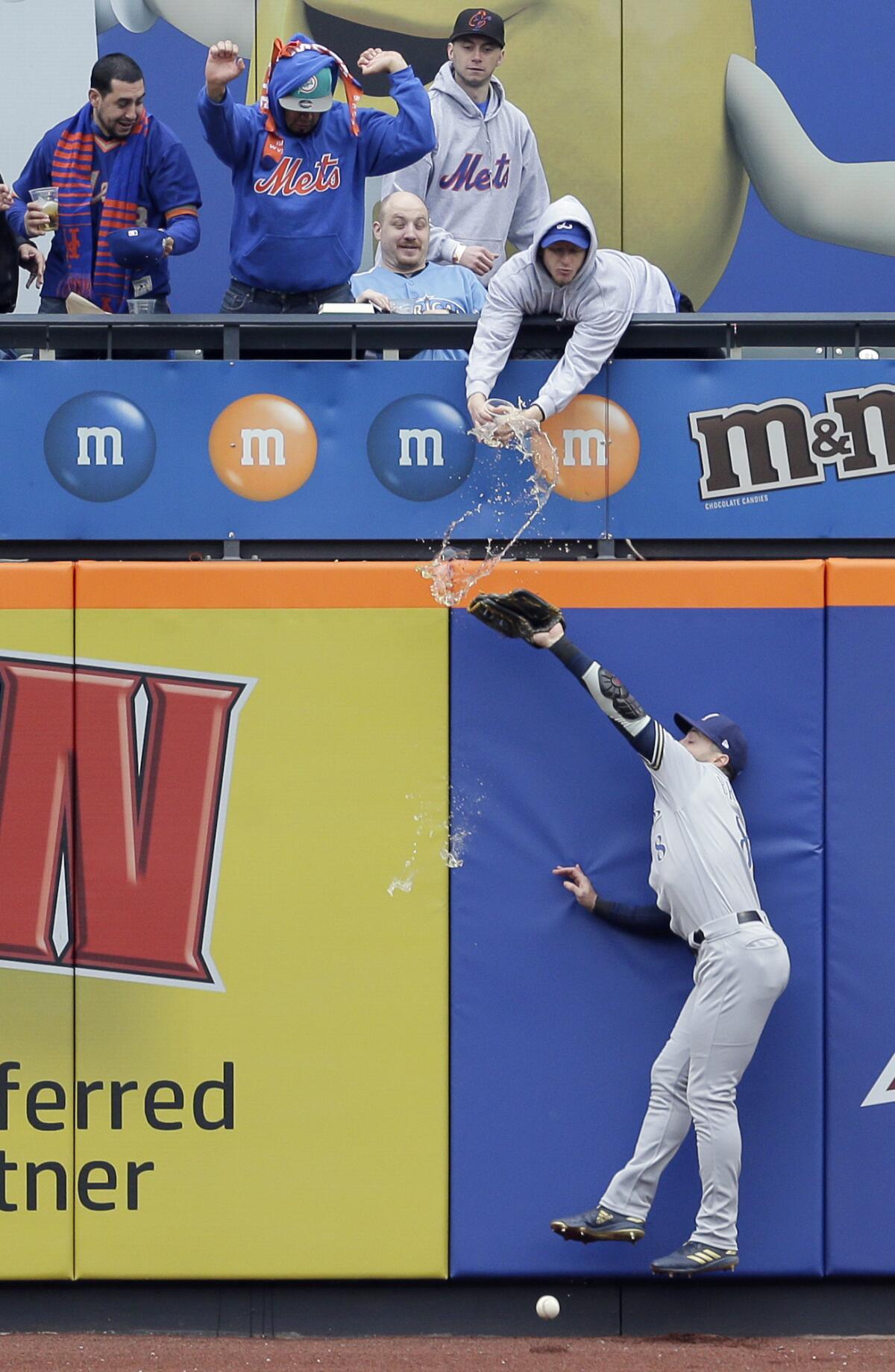 A fan spills beer on the Brewers' Ryan Braun as the left fielder tries but fails to grab a fly ball hit by the Mets' Pete Alonso on Sunday at Citi Field.