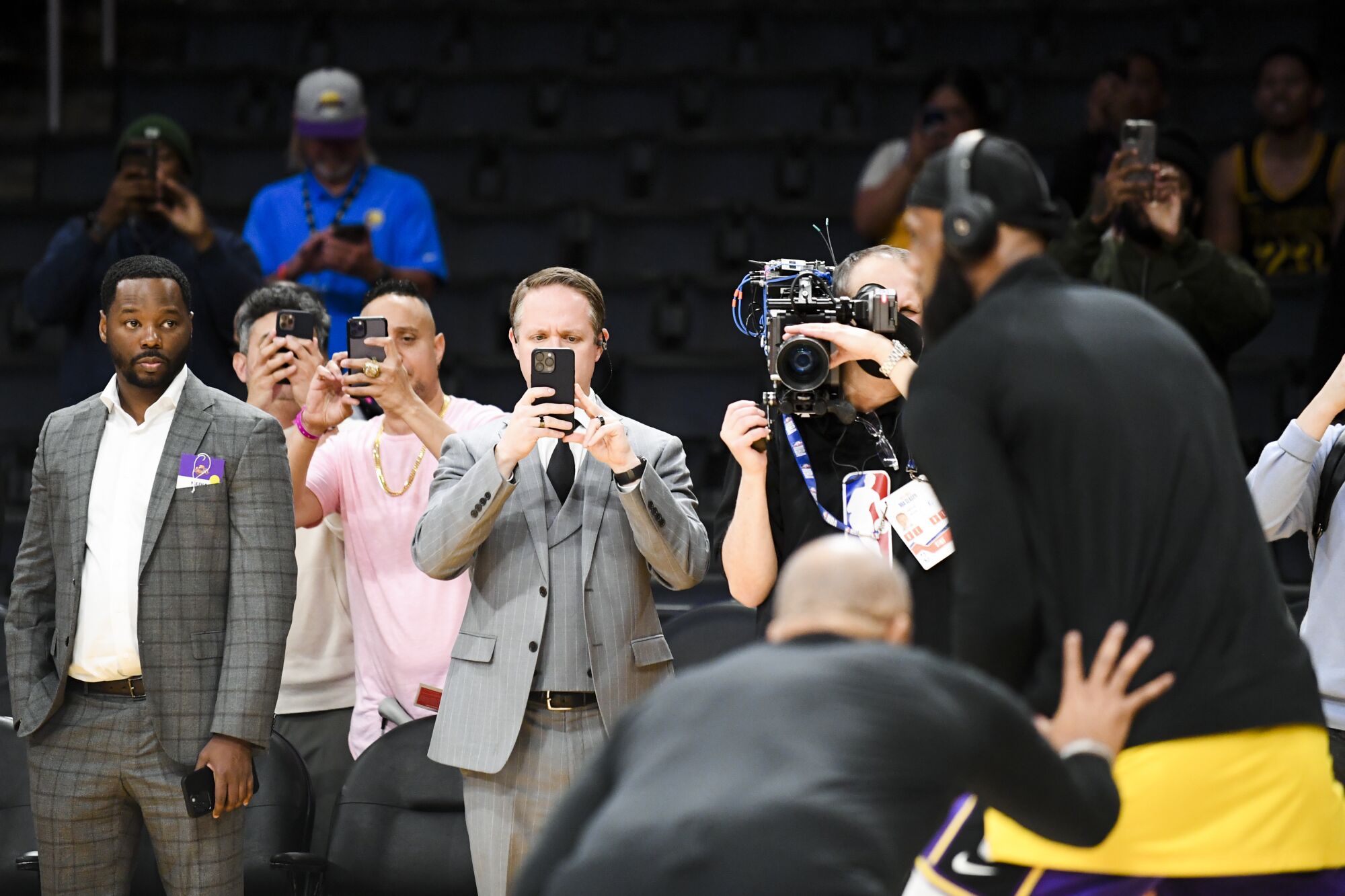 People watch and record on their phones as Lakers forward LeBron James warms up.