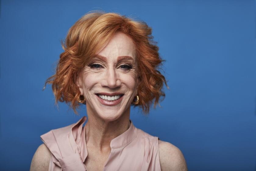 A woman with red hair smiling against a blue background