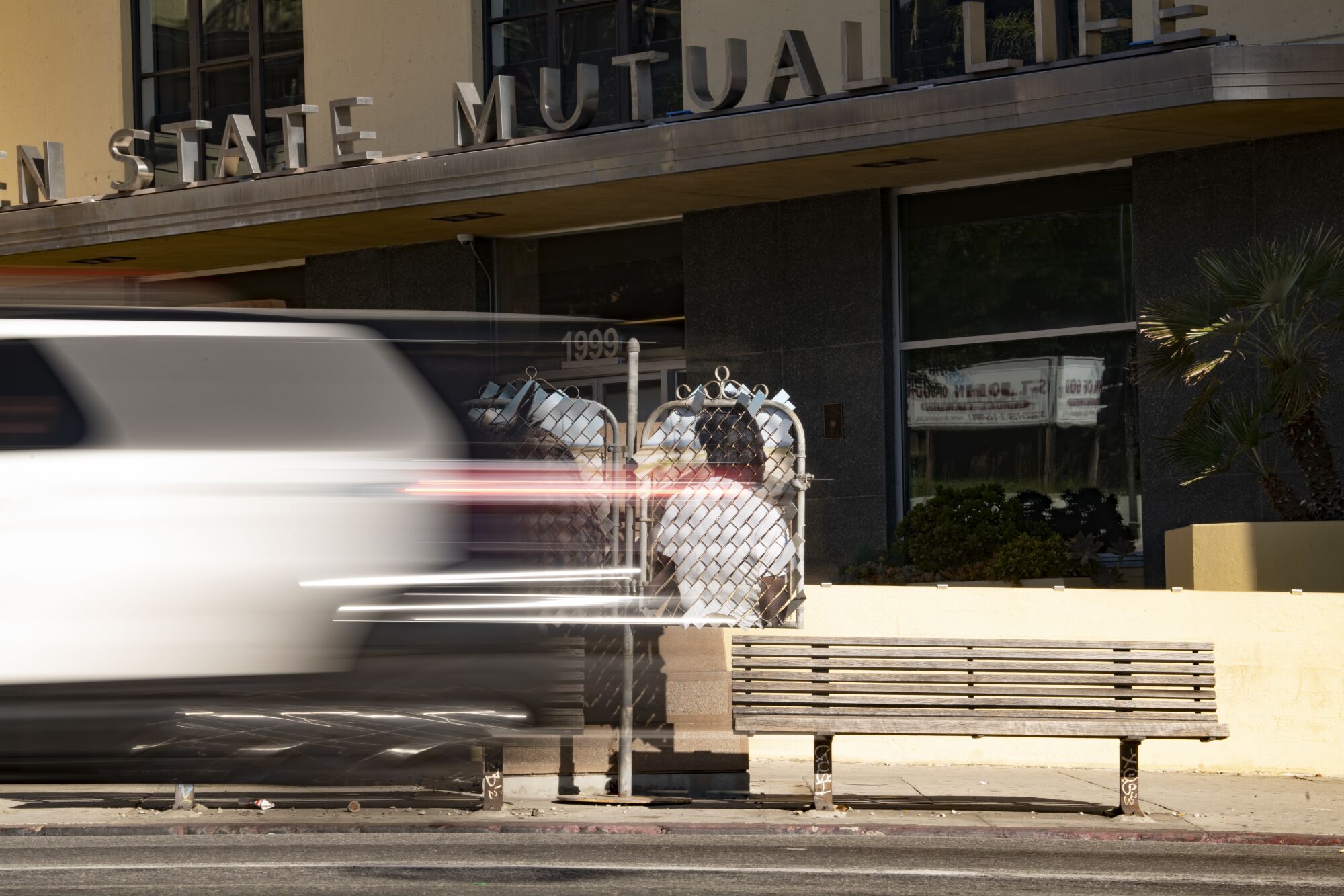 A blurred car passes by "Desert Totem (West Adams, California)" and the Golden State Mutual Life Insurance building.