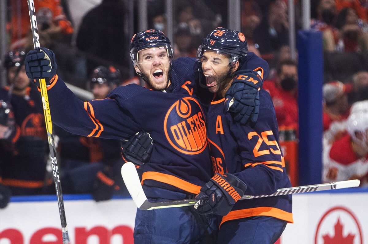 Edmonton Oilers' Connor McDavid (97) and Darnell Nurse (25) celebrate a goal against the Calgary Flames during the second period of an NHL hockey game Saturday, Oct. 16, 2021, in Edmonton, Alberta. (Jason Franson/The Canadian Press via AP)