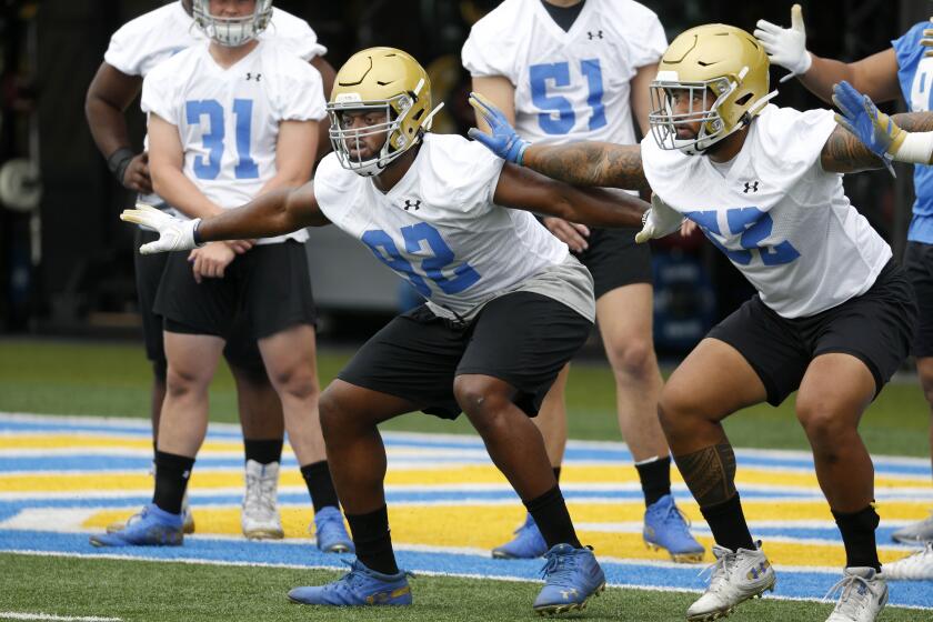 LOS ANGELES, CALIF. -- WEDNESDAY, JULY 31, 2019: Osa Odighizuwa (92), defensive line, and Lokeni Toailoa (52), right, linebacker, go through punt formation drills at fall football camp practice at the football fields at the Wasserman Football Center on the campus of UCLA in Los Angeles, Calif., on July 31, 2019. (Gary Coronado / Los Angeles Times)