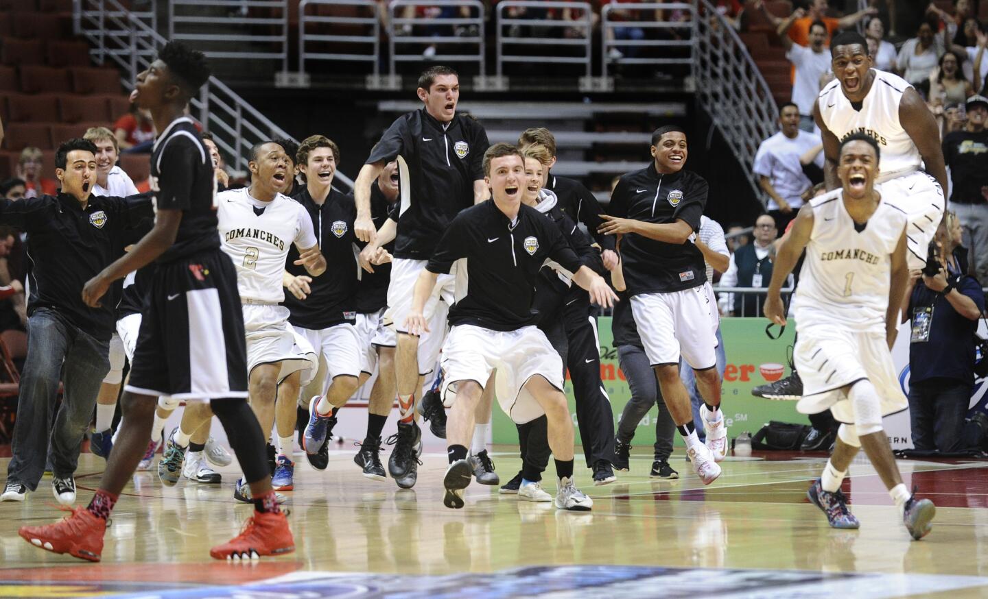 Canyon players celebrate at the end of the game as Lawndale's Deandre Snedecor,left, walks off the court after the Southern Section Division 2AA championship game Saturday at the Honda Center Saturday. The Comanches came back from a 28-point defecit to win in double overtime.