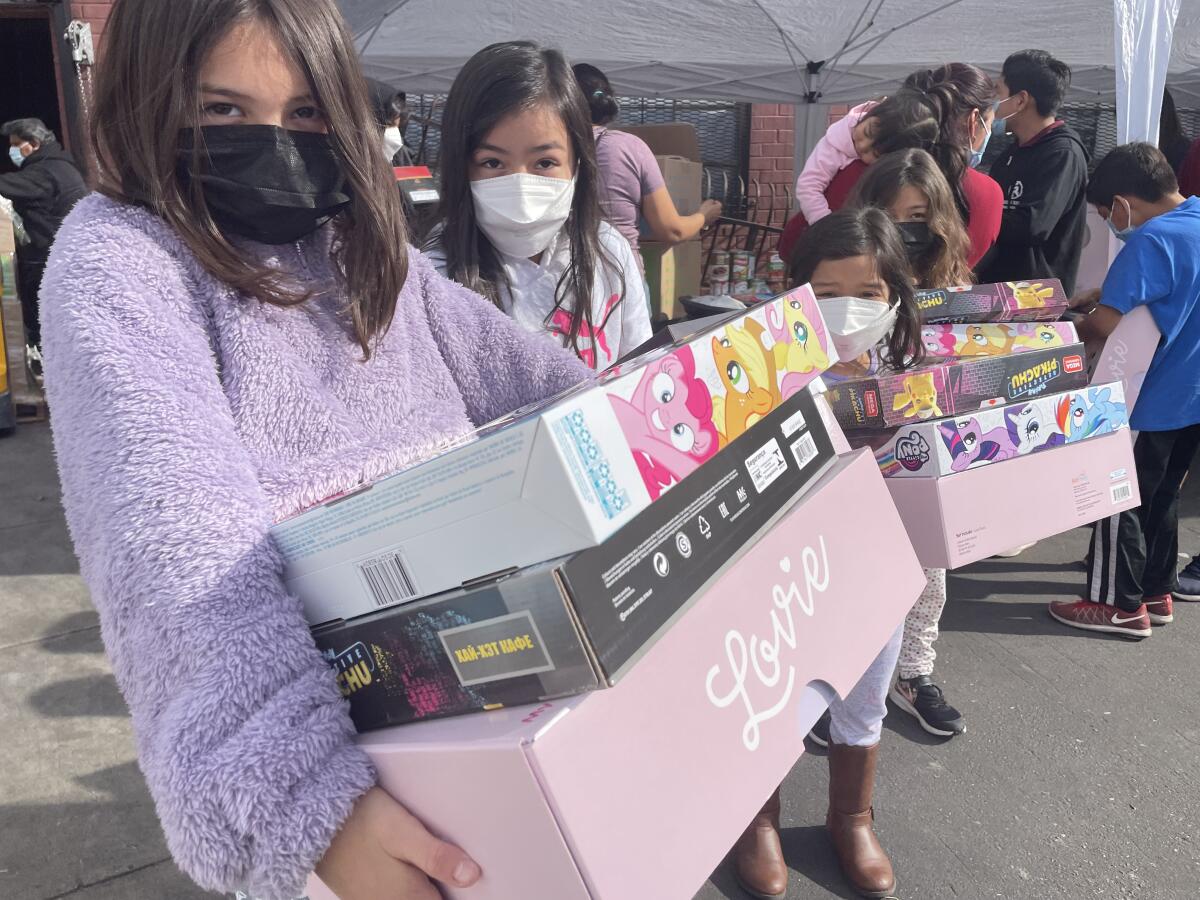 Un grupo de niñas sale con sus juguetes en mano del banco de comida Monte Sion Center, ubicado en el Este de Los Ángeles.